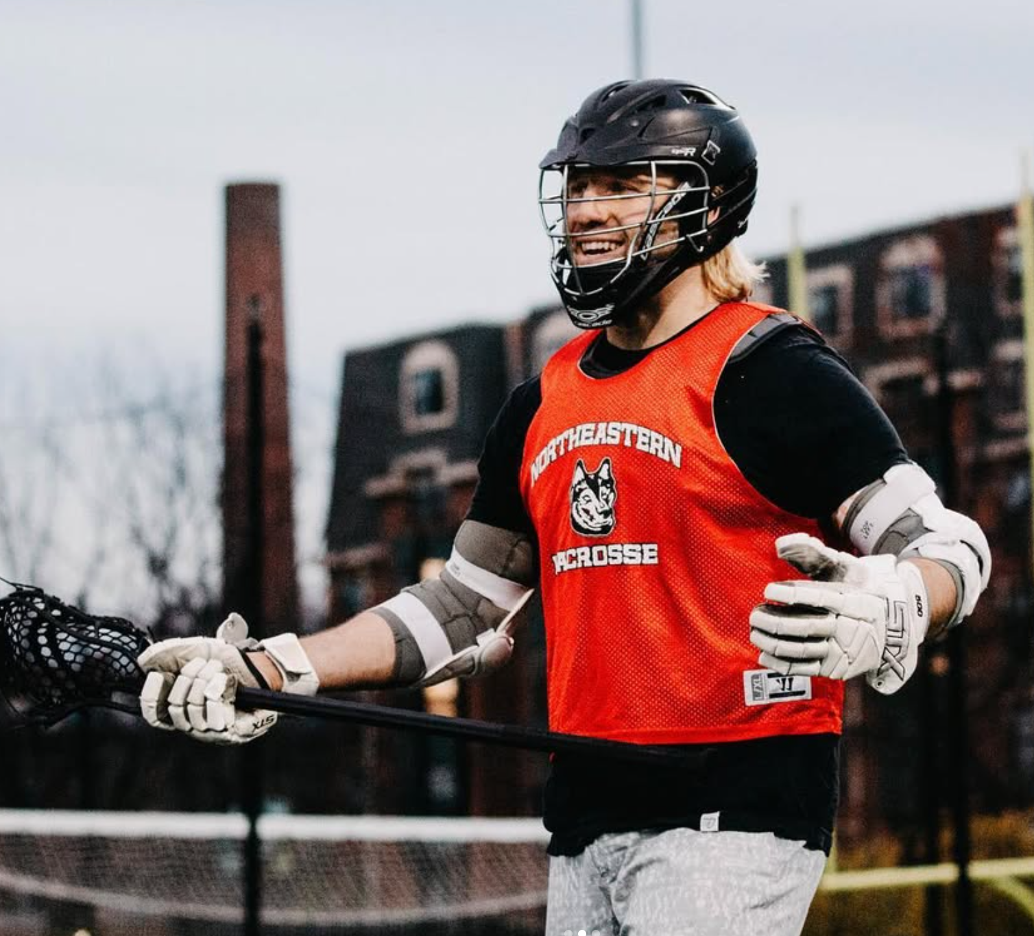 Brett Fink in his Northeastern Lacrosse jersey, wearing a helmet and holding his stick